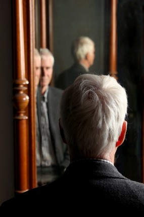 Eine männliche Person, Gernot Böhme, blickt in einen Spiegel und wird mehrfach reflektiert.