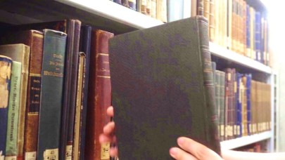 Ein Buch wird aus dem Magazinregal entnommen.